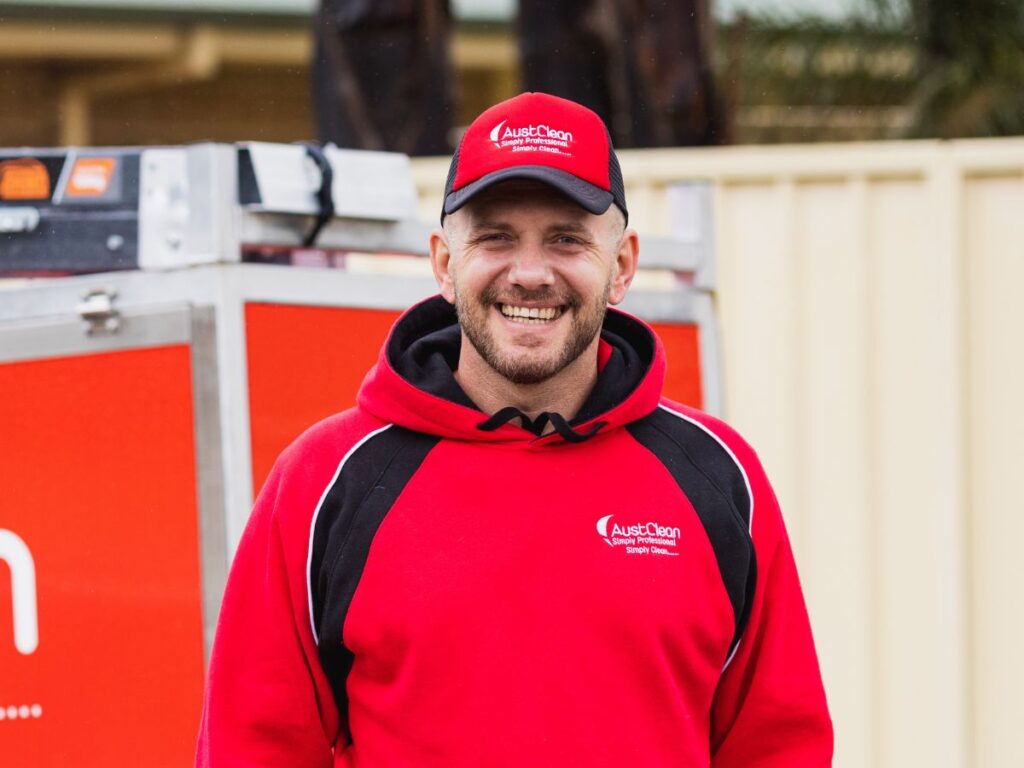 Friendly AustClean cleaning technician in company uniform and cap, representing professional and reliable cleaning services for homes and businesses across Australia.